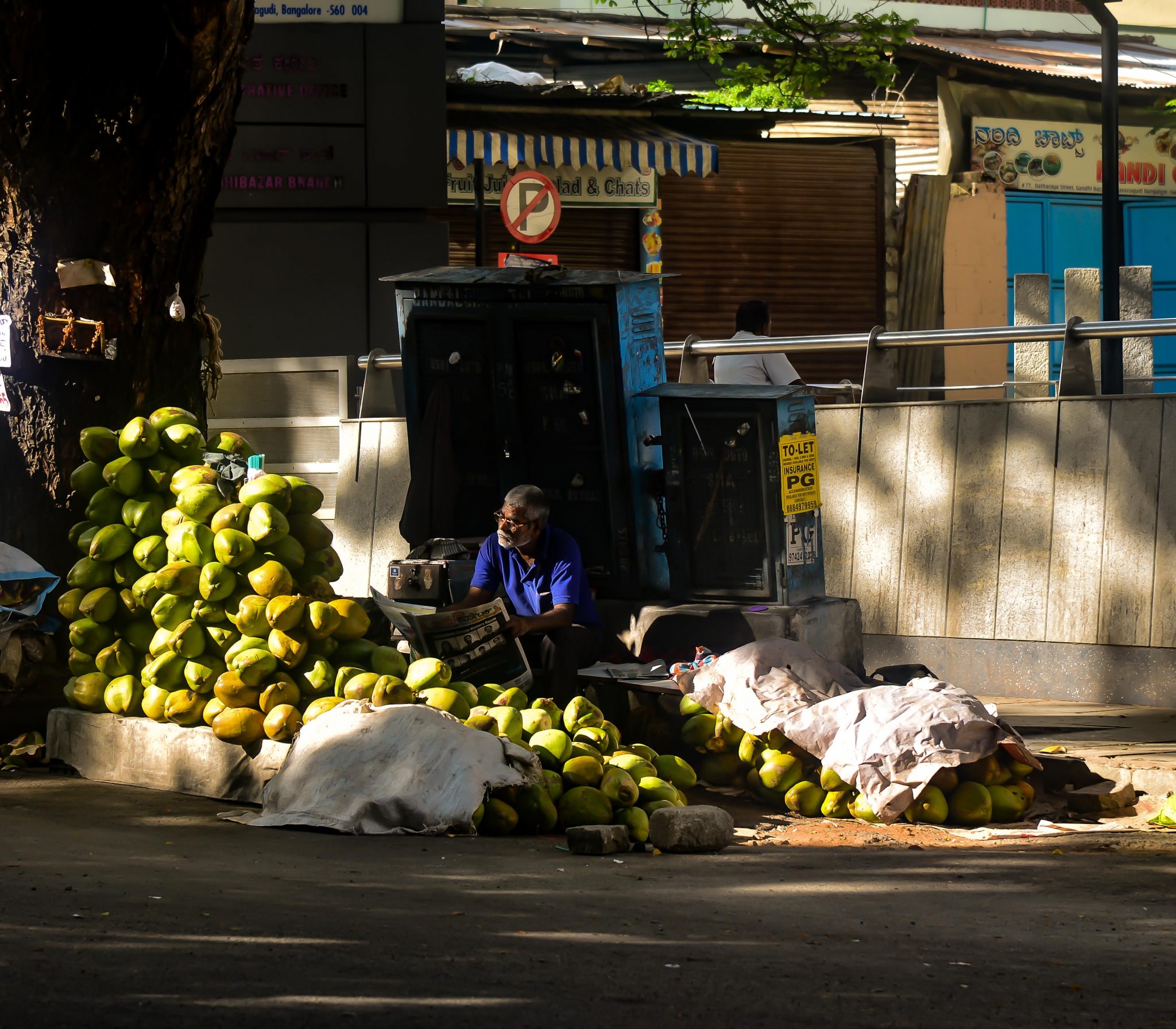 A tender coconut vendor takes advantage of a lull in sales to catch up on the daily news. Photo credit: Suri Venkatachalam A tender coconut vendor takes advantage of a lull in sales to catch up on the daily news. Photo credit: Suri Venkatachalam