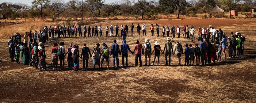 People standing in a circle holding hands in an empty field