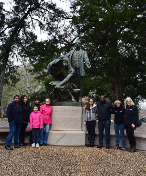 A group of people posing for a photo in front of a statue