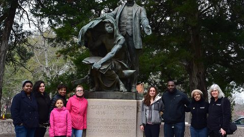 A group of people posing for a photo in front of a statue