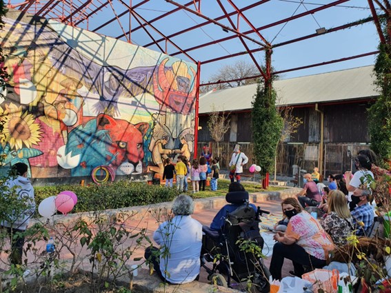 A group of people sitting and watching a performance in an outdoor area