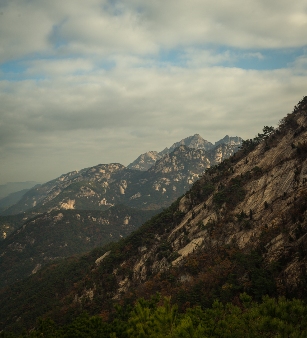 A cliffside with mountains beyond it