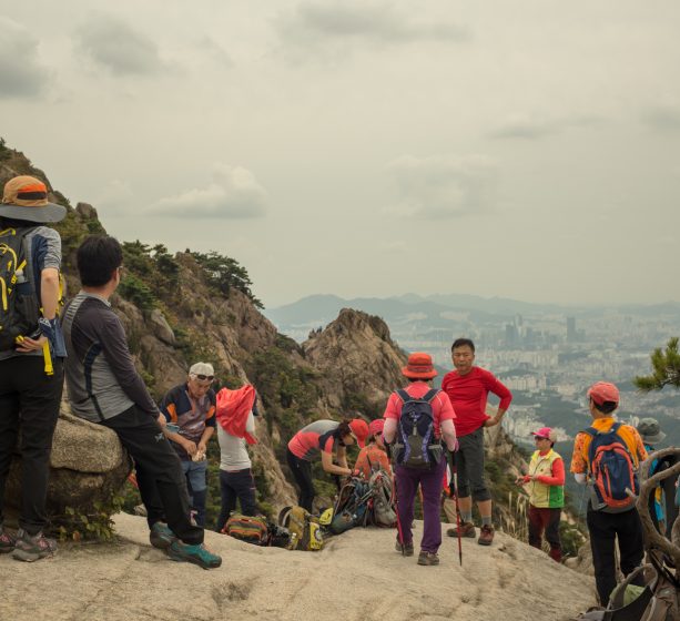 People standing and resting on a mountain path overlooking a city