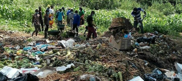 A picture of a field full of trash and people standing next to it with bags