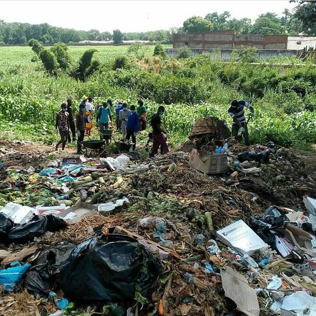 A picture of a field full of trash and people standing next to it with bags