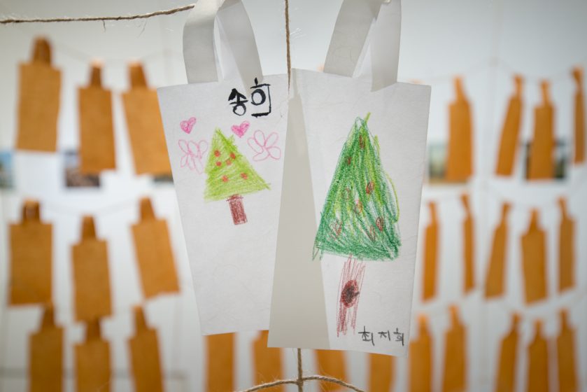 A picture of colored pencil drawings of cedar trees hanging from a string