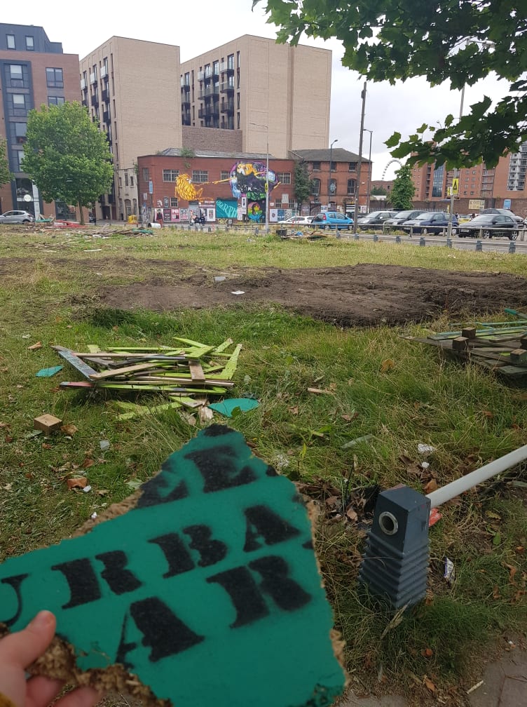 A picture of a field with broken pieces of wooden signs and trash scattered everywhere