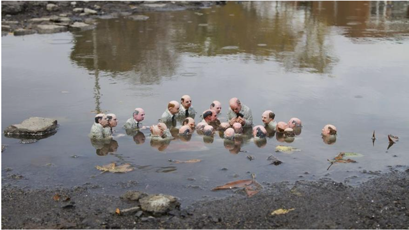 A group of bald men dressed alike shoulder-deep in a body of water