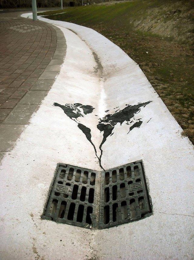 A picture of street art depicting the world map flowing down a drain