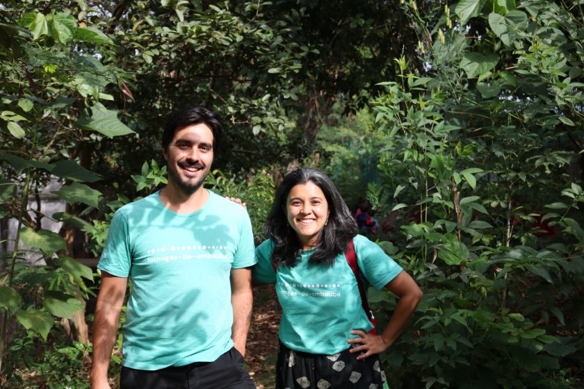 A picture of two people in teal shirts standing on a path in the forest