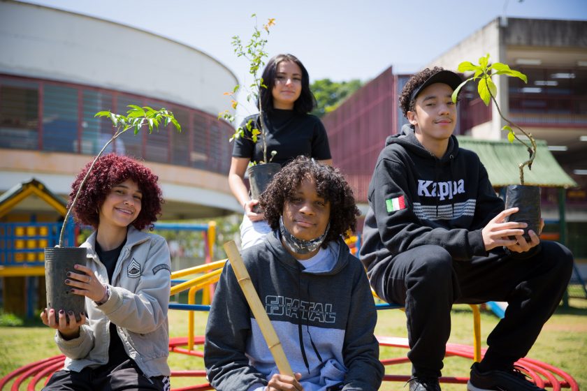 A picture of four kids sitting on outside bleachers all holding potted plants