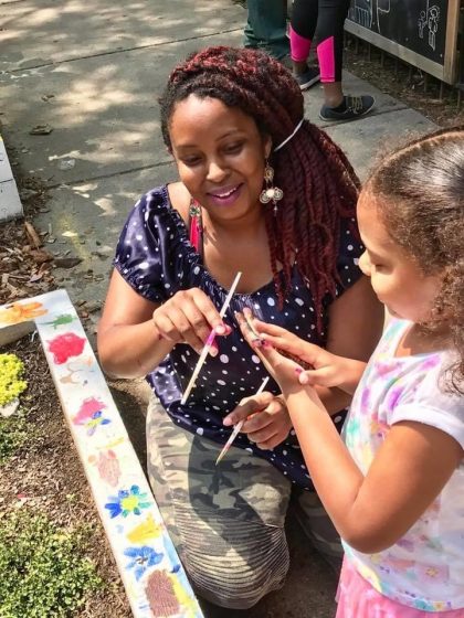 A picture of a woman and a child painting a flowerbed