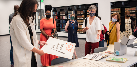 A picture of a group of people in a library standing around a table