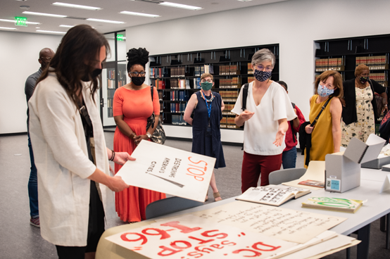 A picture of a group of people in a library standing around a table