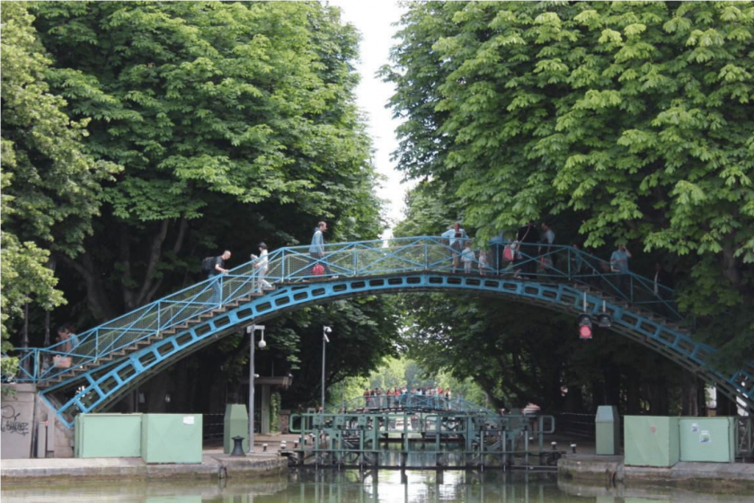 A picture of people walking across a metal bridge over water