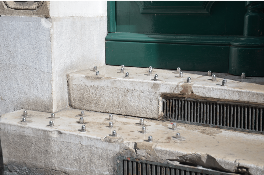 A picture of a concrete stoop with metal spikes embedded on it