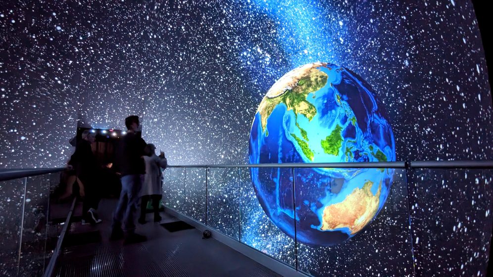 A picture of people walking through a 3-D projection of space