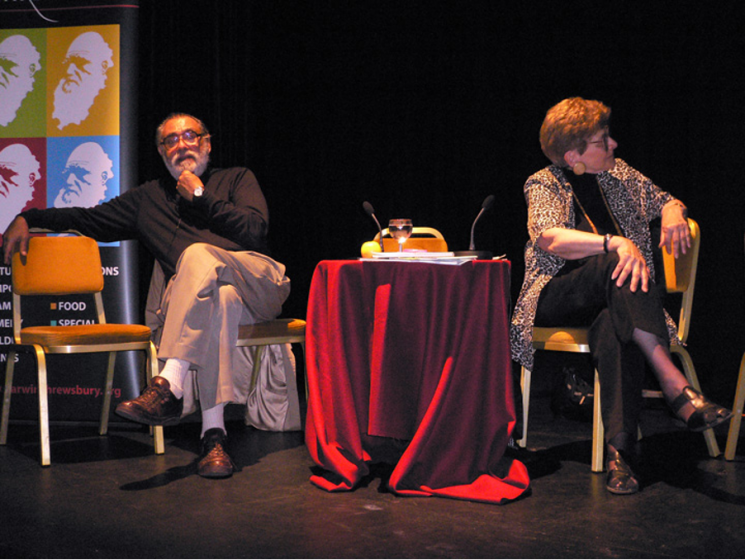 A picture of two people sitting on chairs on a stage
