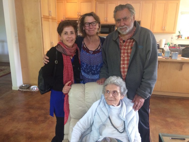 A picture of three smiling people standing behind a smiling woman sitting in a chair