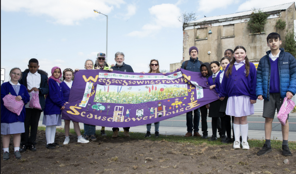 A picture of a group of people outside holding a banner