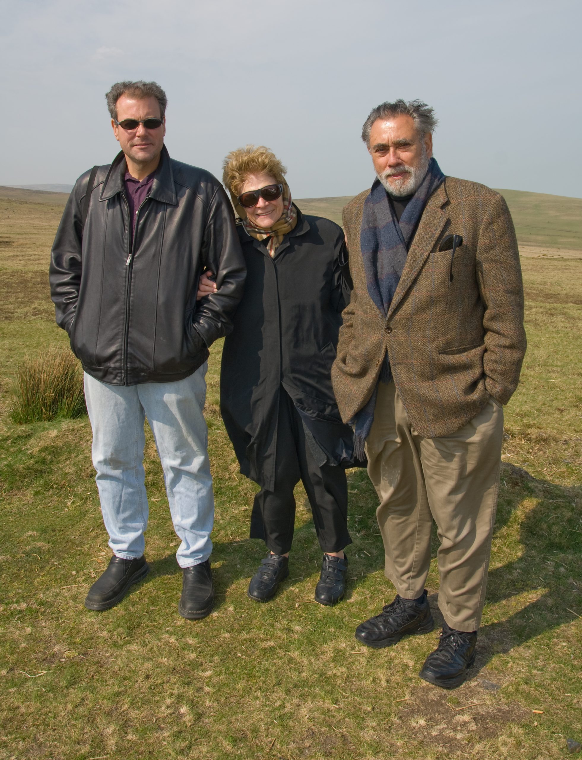 A picture of three people standing together in a field smiling