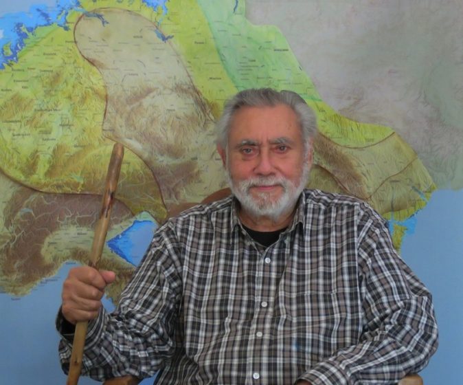 A picture of a man standing in front of a map and smiling