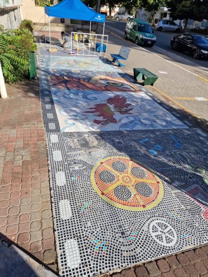 A picture of a sidewalk with various colorful paintings
