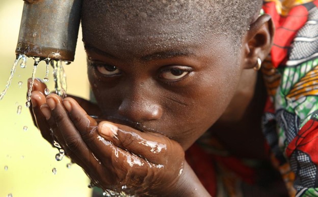 A picture of a young girl drinking water from her cupped hands