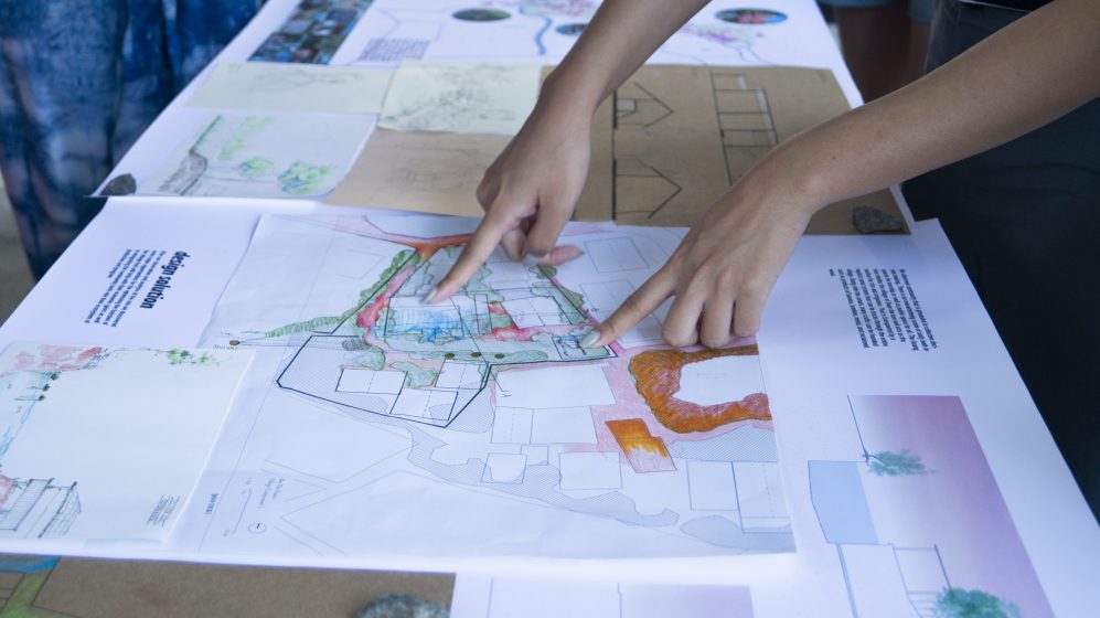 A picture of hands pointing at a map on a table