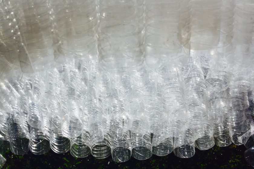 A closeup view of many plastic bottles with one end cut off, arranged tightly together.