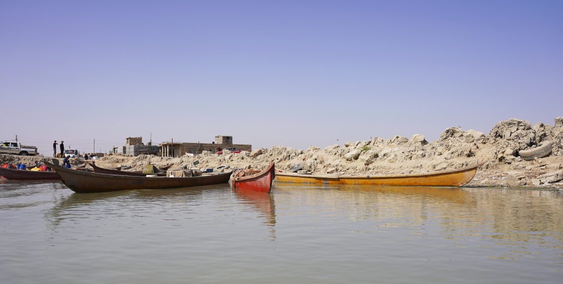 Multiple longboats docked on a rocky, desolate-looking land.
