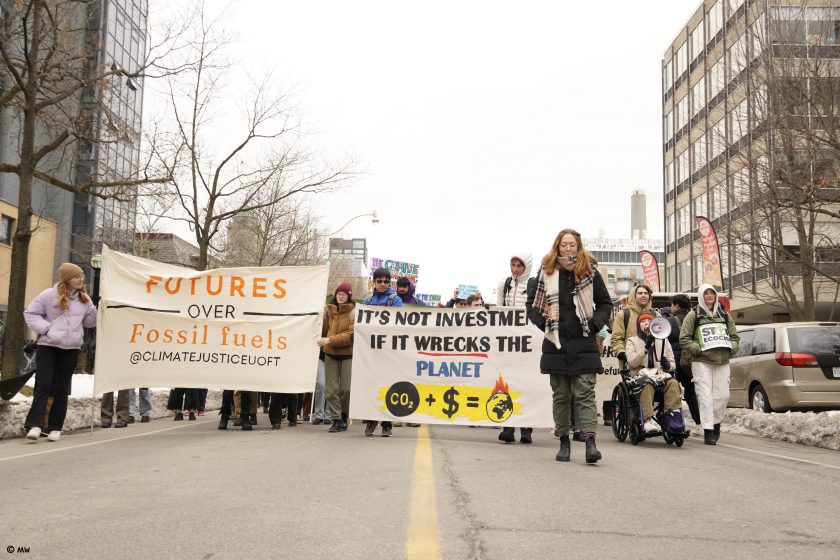 A group of people marching in a street holding signs