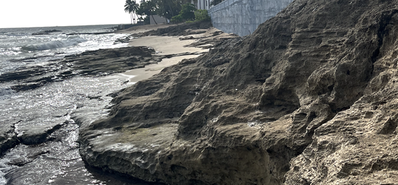 A rocky beach with a building in the background