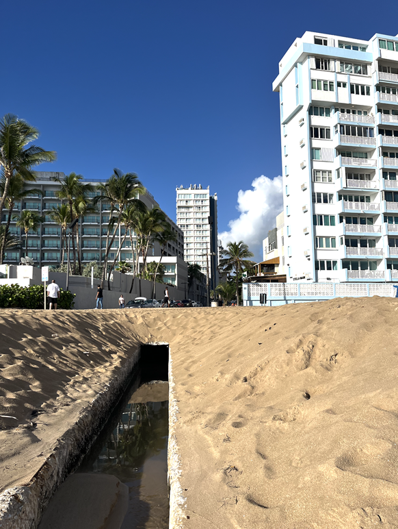 A sand beach and water in front of buildings