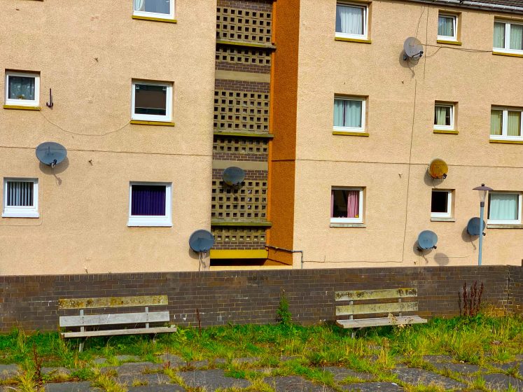 A multi-level apartment building with small windows and benches outside