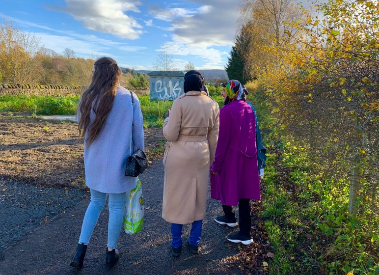 A group of women walking on a path through a vegetated area