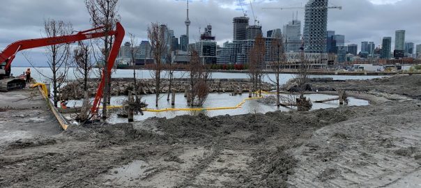 A muddy work site with a city in the background