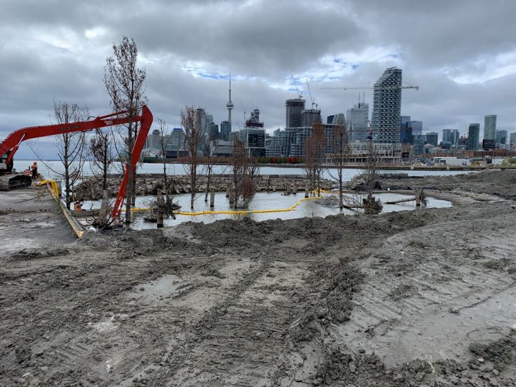 A muddy work site with a city in the background