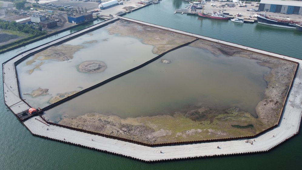 A large area of water with an octagonal dock in the center of it filled with muddy water