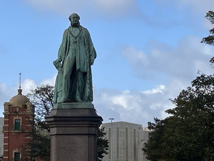 A green statue of a person in a coat