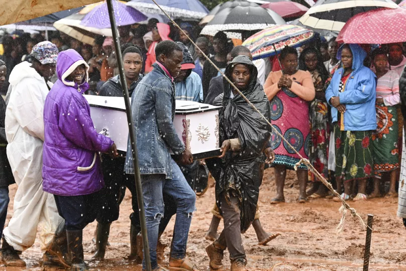 A group of people carrying a coffin through muddy water and rain