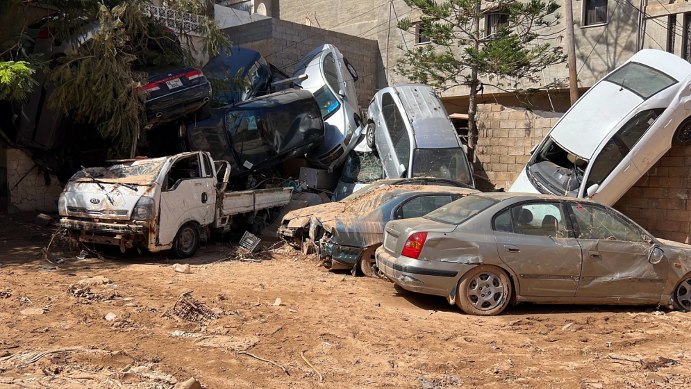 A large group of piled up, crashed cars in muddy flood waters