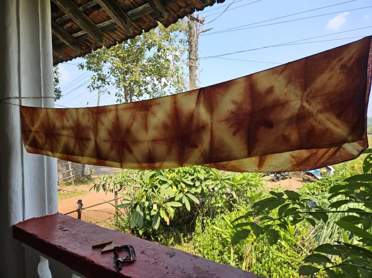 A long piece of rusty orange fabric with X patterns dyed into it