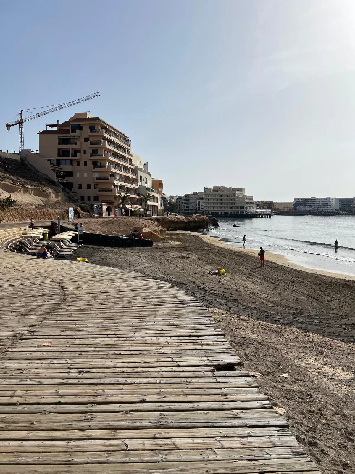 A wooden walkway on a beach leading toward a building
