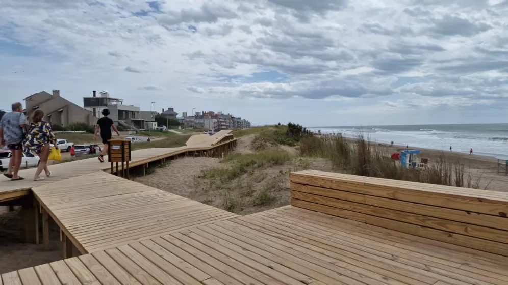 A wooden deck with a beach and buildings in the background