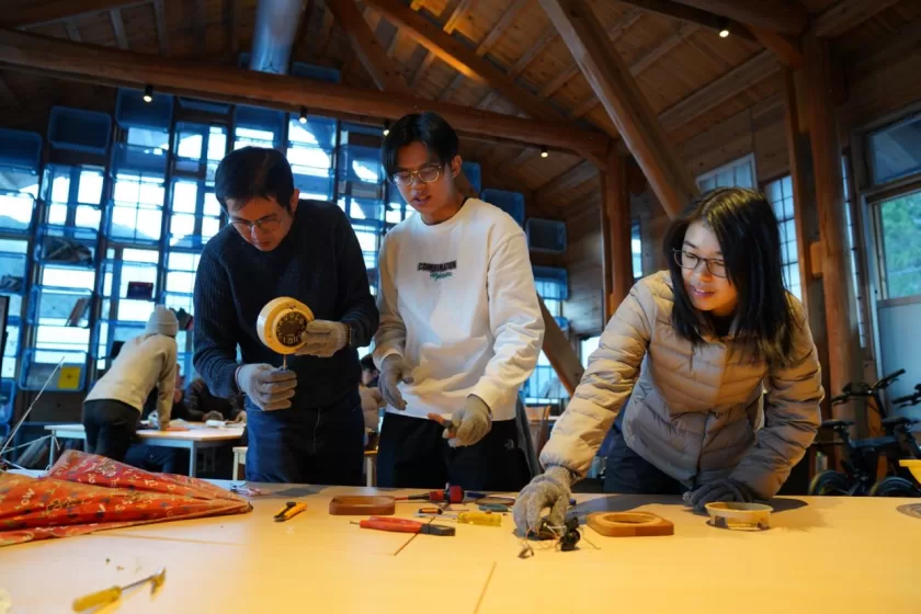 A group of people working on creating umbrellas on a wooden table