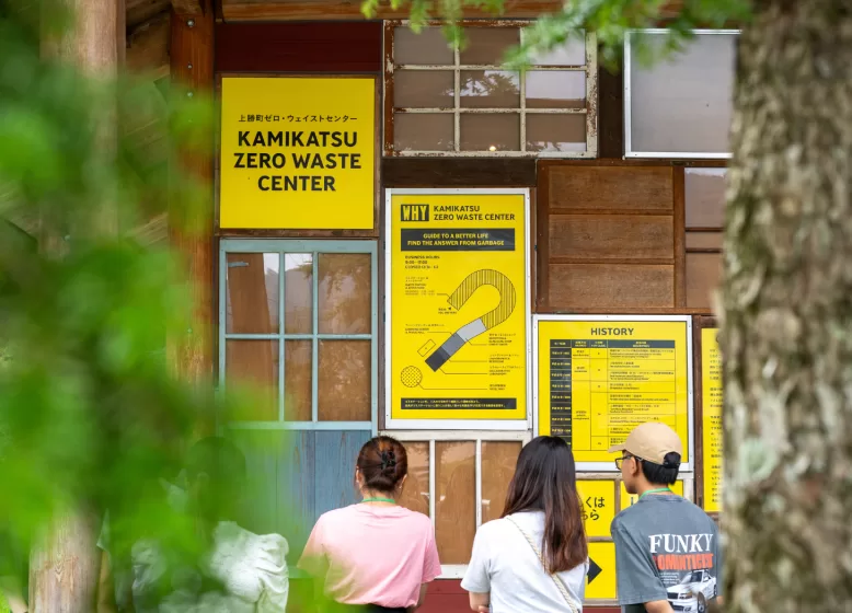 A group of people standing outside a building with yellow signs with maps