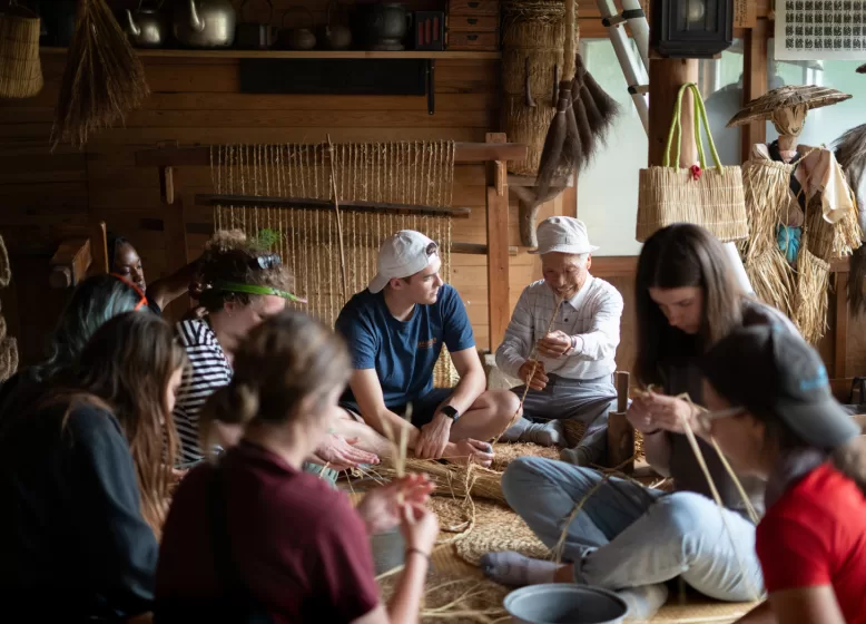 A group of people sitting on the floor weaving baskets