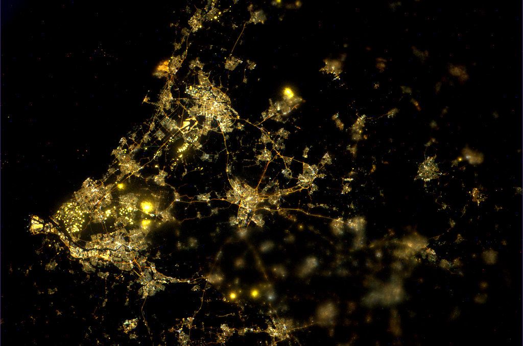 An aerial photo of a city at night. You can only see the powered lights and homes