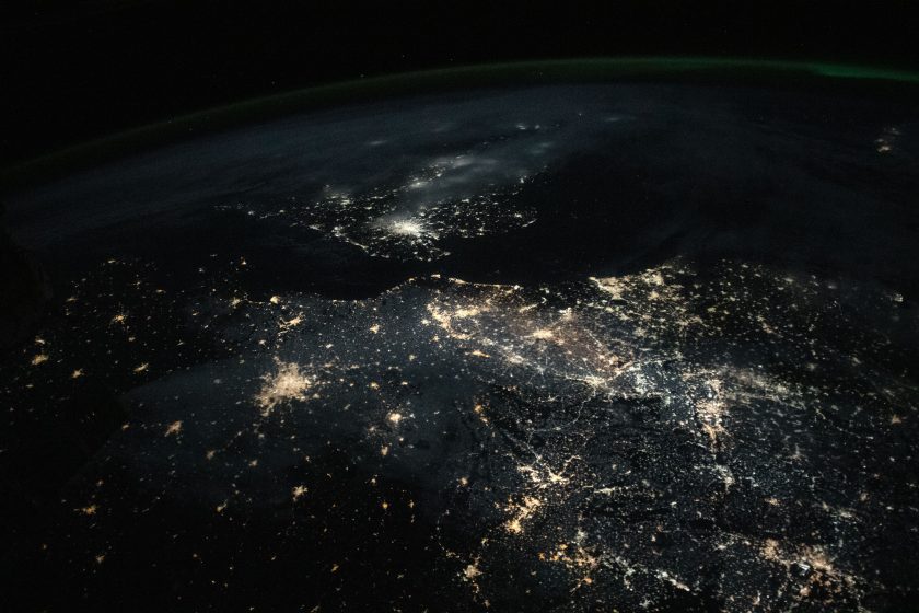 An aerial photo of a city at night. You can only see the powered lights and homes